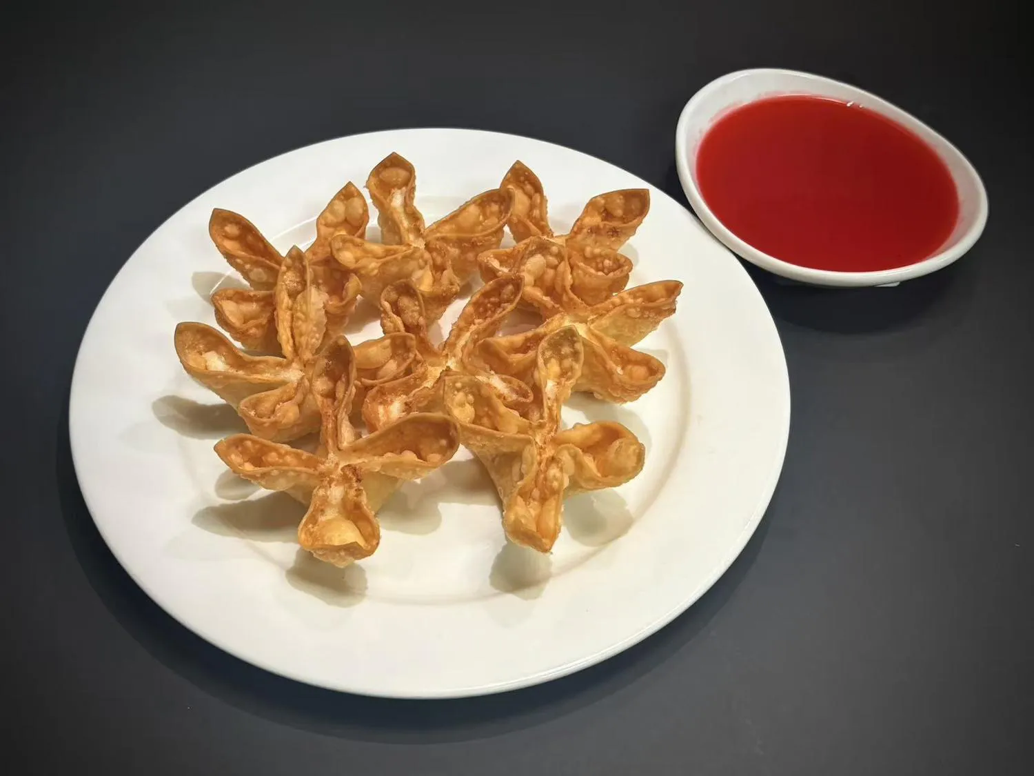 Crispy fried cheese wontons on white plate with red sweet‑sour dipping sauce at Lucky House, a Chinese restaurant in Surprise Crispy fried cheese wontons on white plate with red sweet‑sour dipping sauce at Lucky House, a Chinese restaurant in Surprise