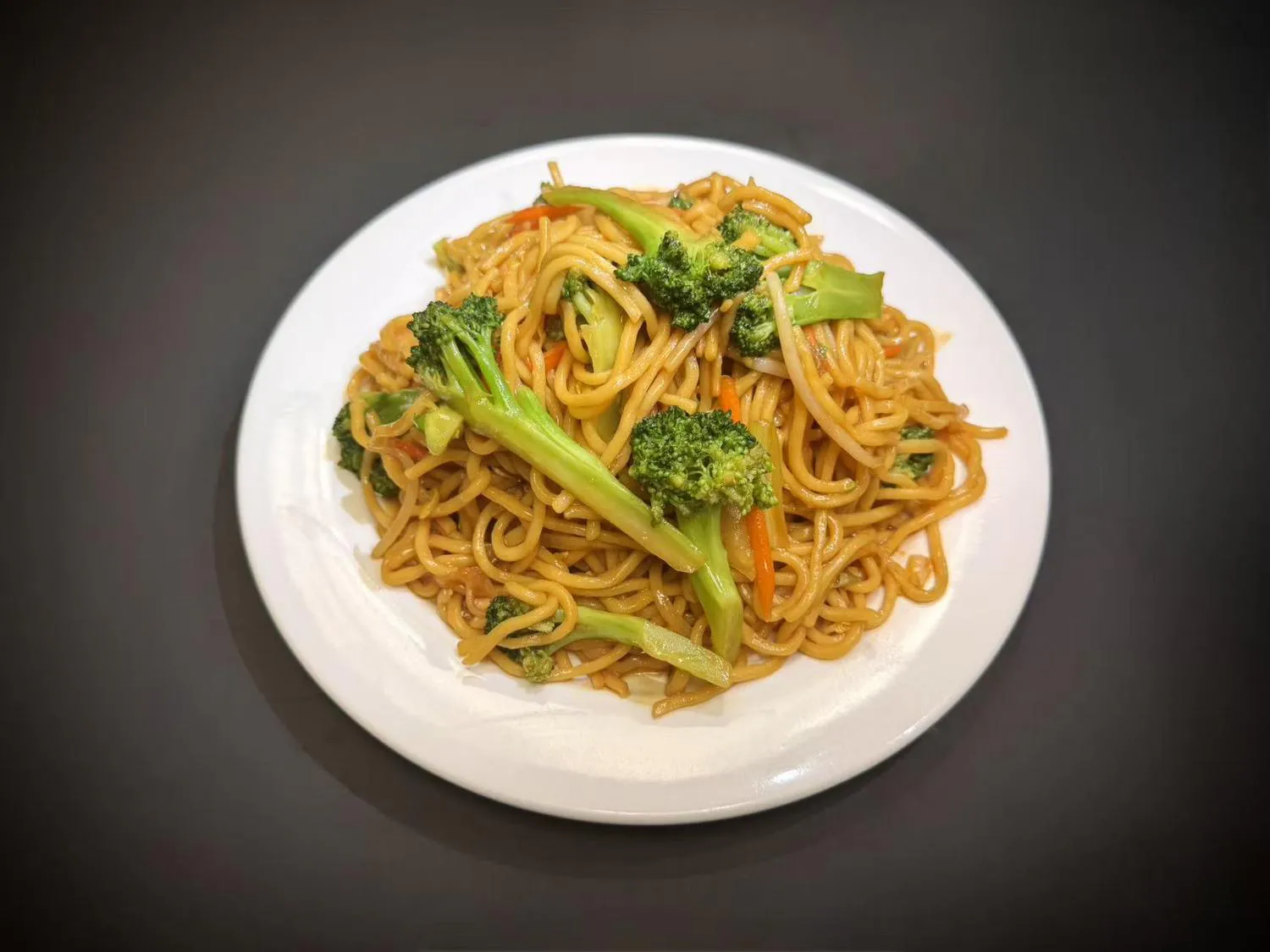 Vegetable lo mein noodles topped with fresh broccoli and carrot strips on white plate at Lucky House, a Chinese restaurant in Surprise Vegetable lo mein noodles topped with fresh broccoli and carrot strips on white plate at Lucky House, a Chinese restaurant in Surprise